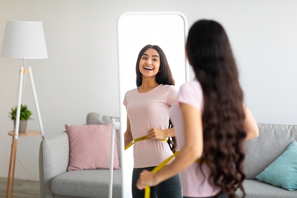 Woman looking in mirror, excited by weight loss