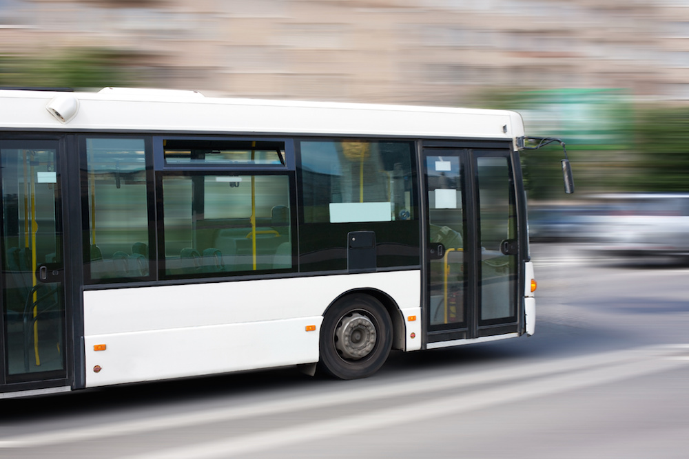 White public bus speeding on a freeway
