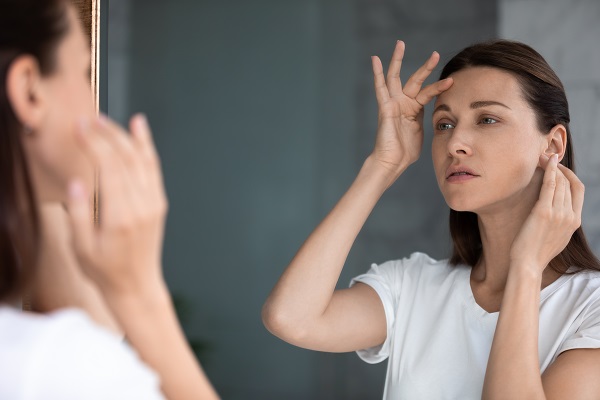 Woman looking in mirror at forehead wrinkles