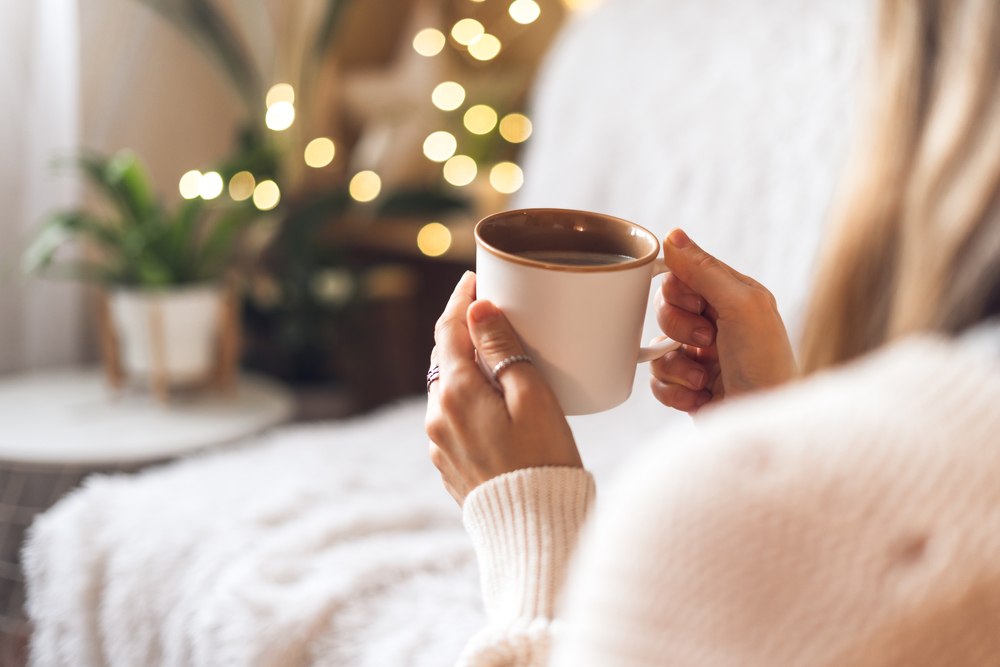 A close up of a woman relaxing on her couch with a cup of hot tea