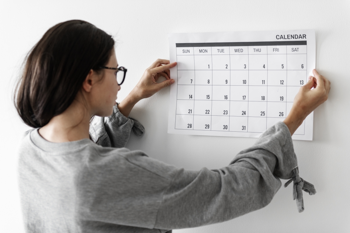 woman pinning a calendar on the wall