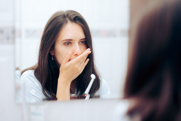 Woman holding hand over mouth after brushing teeth. Probably worried about gum disease.