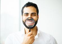 Salt Lake City man inspects his teeth using magnifying glass.
